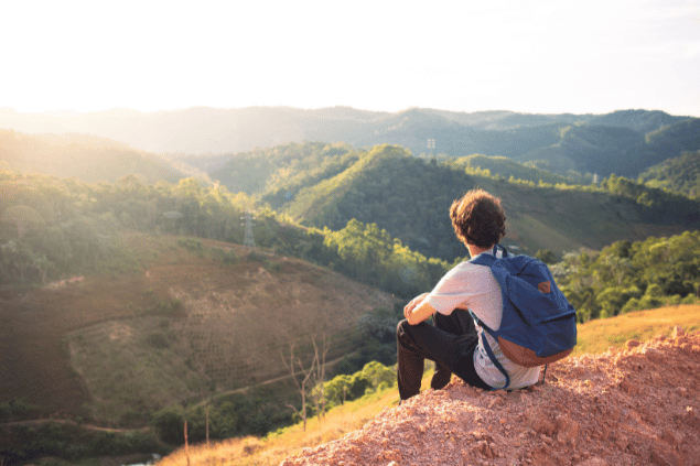 goodapp de Getty Images Pro / Canva Homem sentado em cima de uma pedra enquanto observa várias montanhas
