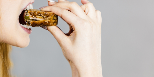 Mulher comendo sanduíche.