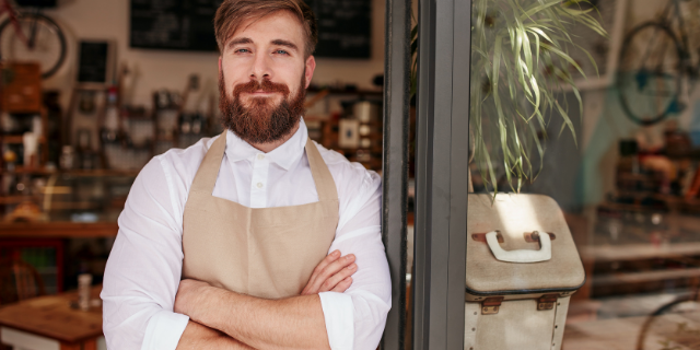 Homem com os braços cruzados sorri. 