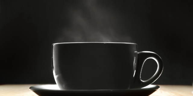 Xícara preta sobre pires. 