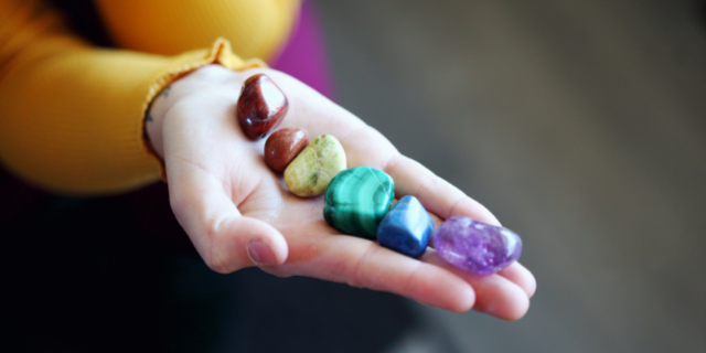 Mulher segura pedras representativas dos chakras. 
