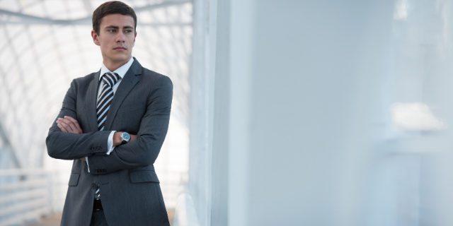 Homem de braços cruzados olha para ponto aleatório. 