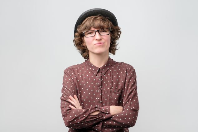 Imagem de uma mulher de óculos w chapéu olhando para frente com uma feição de desprezo