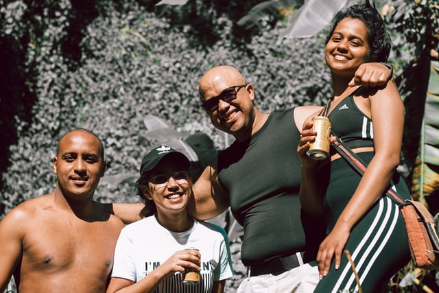 Amigos abraçados com expressões sorridentes.