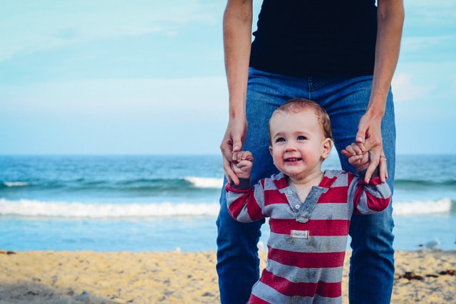 Bebê branco sorrindo na praia.