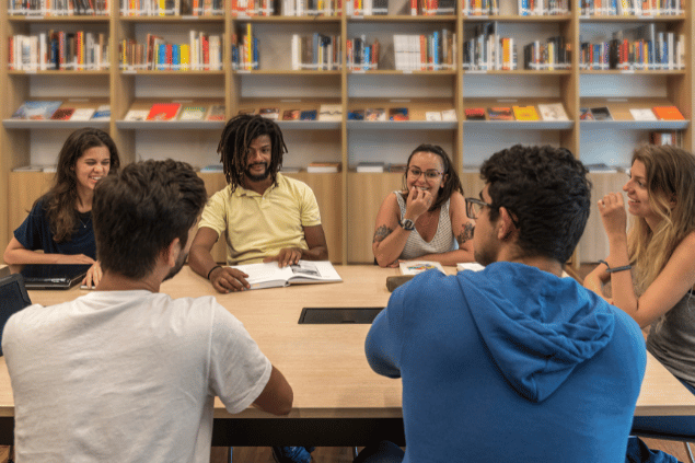 Pessoa sentadas em uma mesa debatendo e estudando