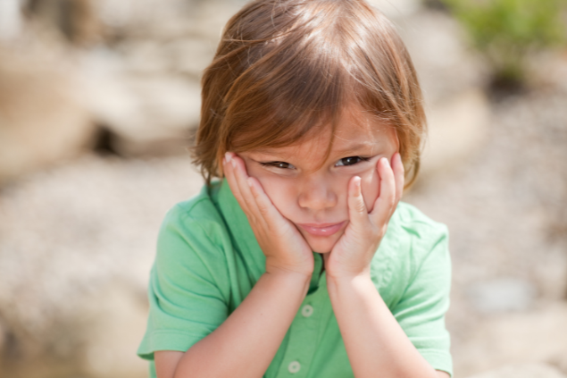 Criança pequena com as mãos no rosto
