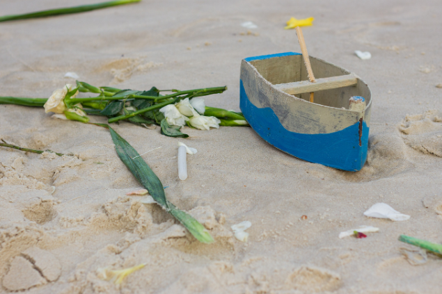 Oferendas na areia, como barquinhos de madeira e rosas