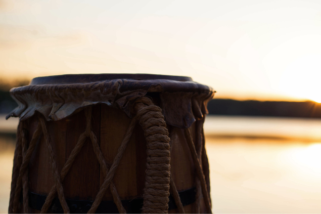 Atabaque e, no fundo, há um sol se pondo