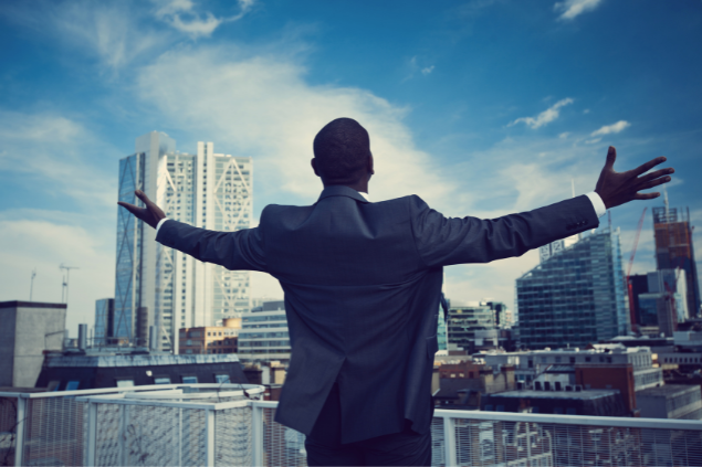 Homem com os braços abertos em direção à cidade