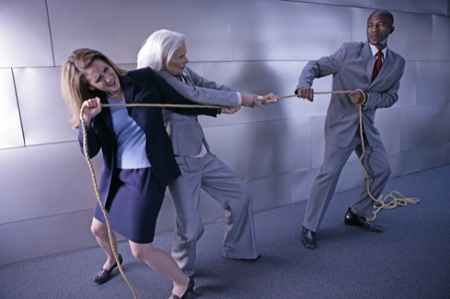 Duas mulheres e um homem puxando um cabo de guerra