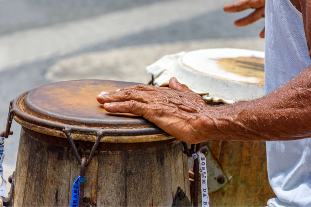 Homem tocando atabaque na praia