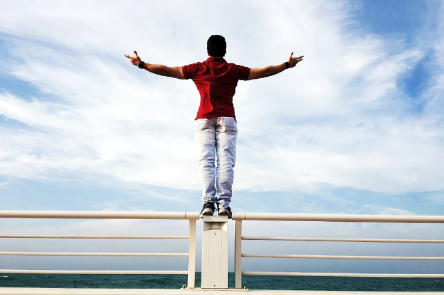 Homem com os braços abertos em cima de um patamar, indicando independência