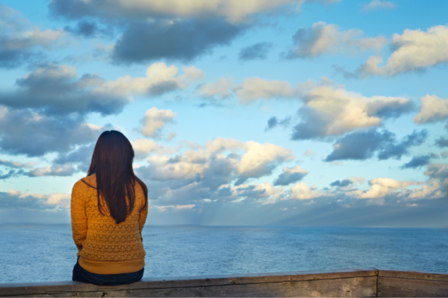Mulher sentada em uma estrutura perto do mar