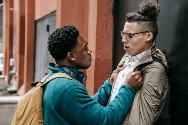 Dois homens brigando na rua contra um muro