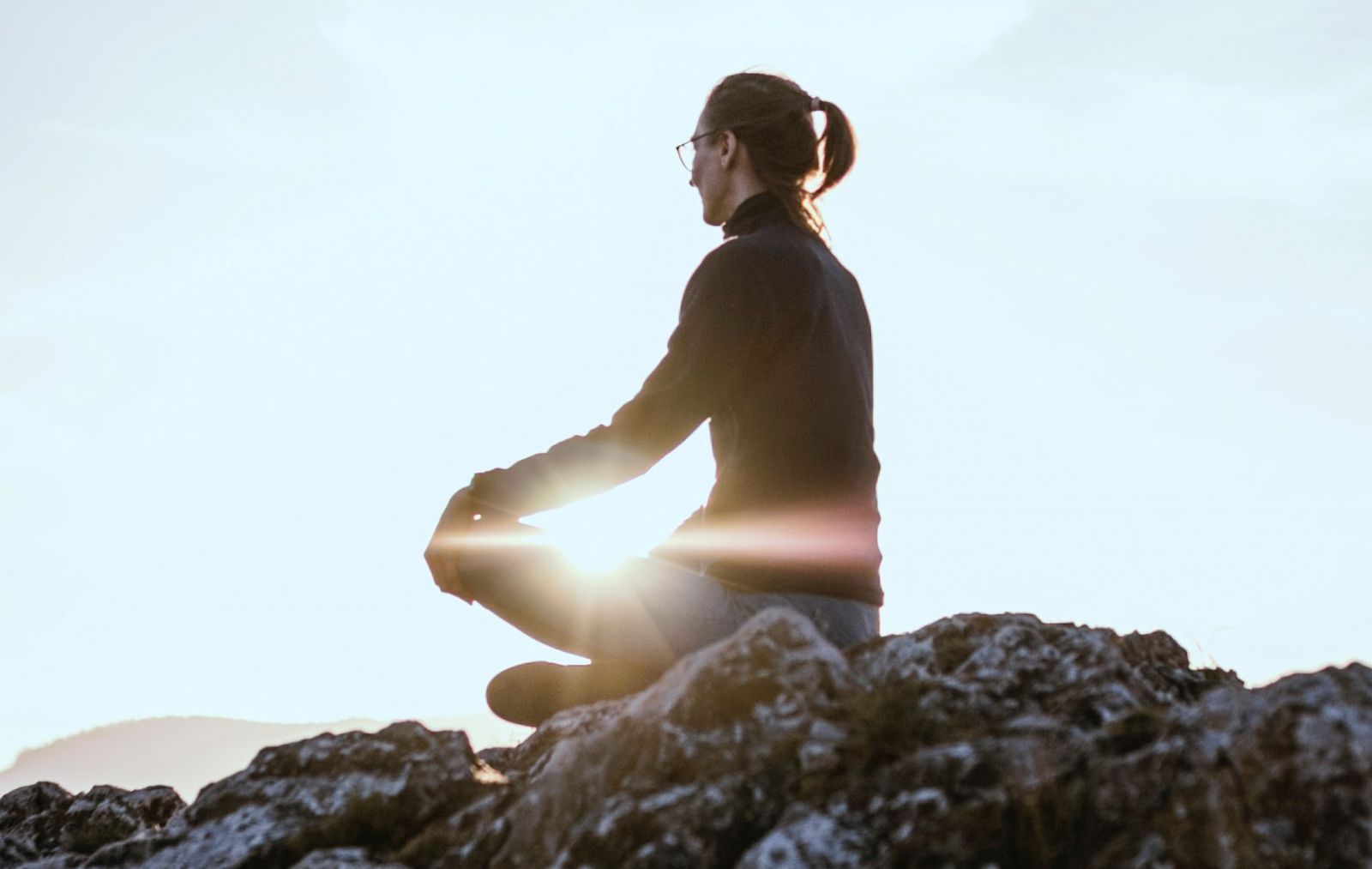 Mulher sentada em pedra em posição de meditação