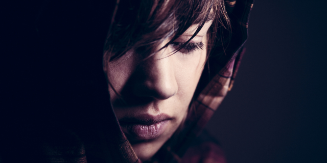 Mulher cabisbaixa e com a franja sobre o rosto. 