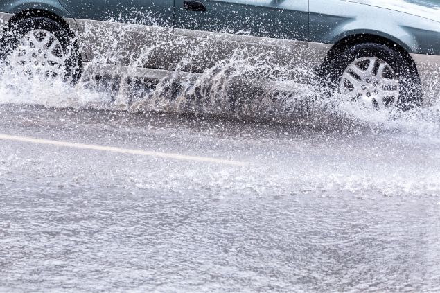 Carro passando ao lado de uma enchente