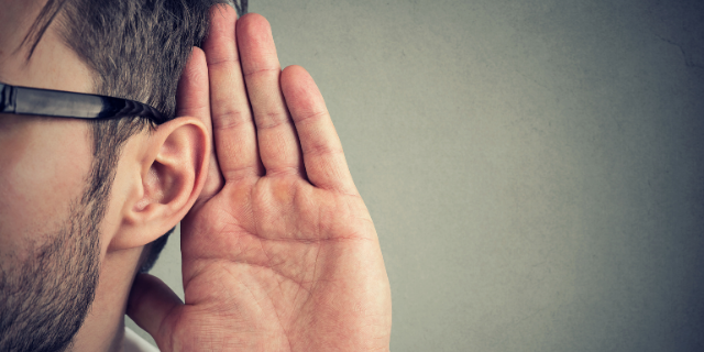 Homem com a mão sob a orelha.