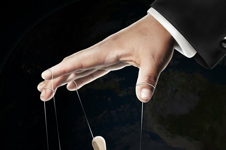 Mão branca masculina manipulando marionete.