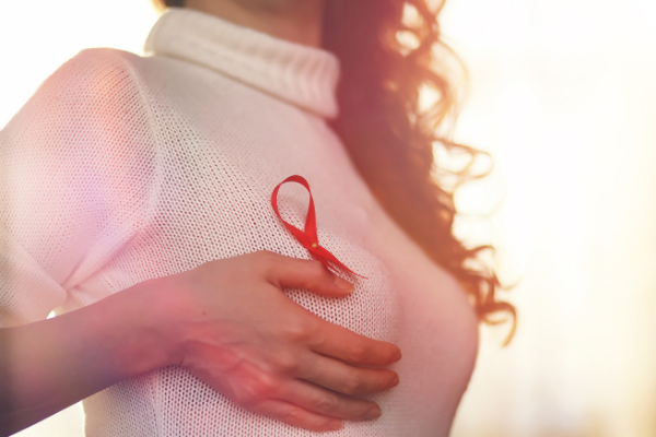 Mulher com a mão sobre o seio e um laço preso em sua blusa
