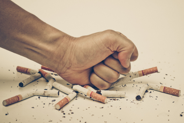 Punho socando cigarros sobre uma mesa