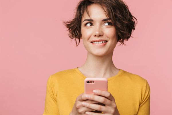 Mulher segurando um celular enquanto olha para o lado, mordendo o lábio.