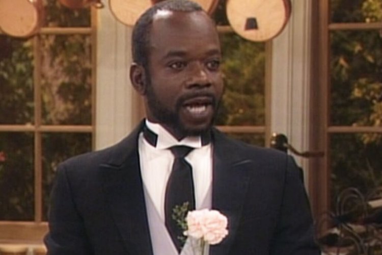 Homem negro de bigode e barba preta, usando smoking.