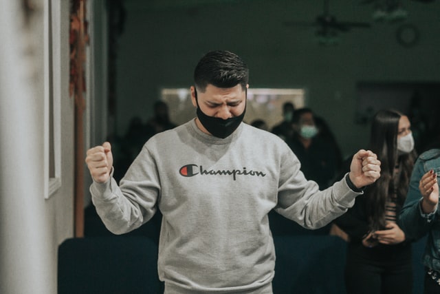 Homem branco com os olhos fechados e punhos levantados.