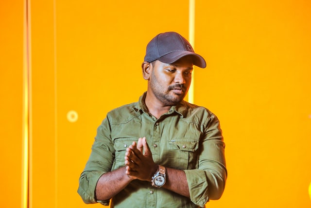 Homem negro com as mãos juntas e olhando para o lado.