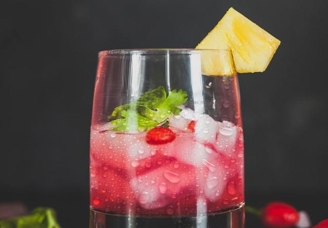 Copo transparente com líquido vermelho e gelo dentro.
