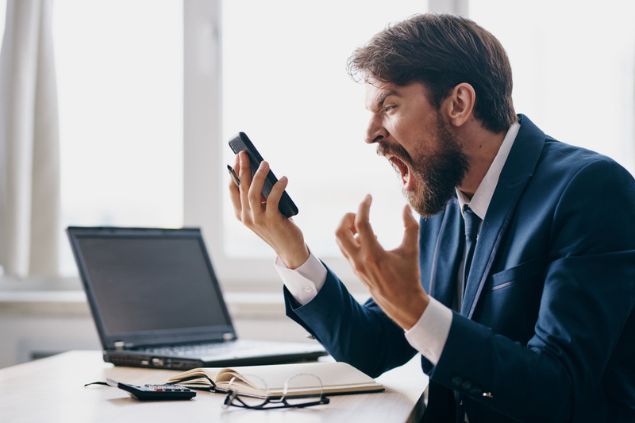 Homem irritado e gritando com seu celular.