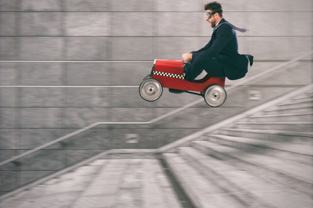 Homem pilotando um mini carro, descendo uma escada com os olhos vendados.