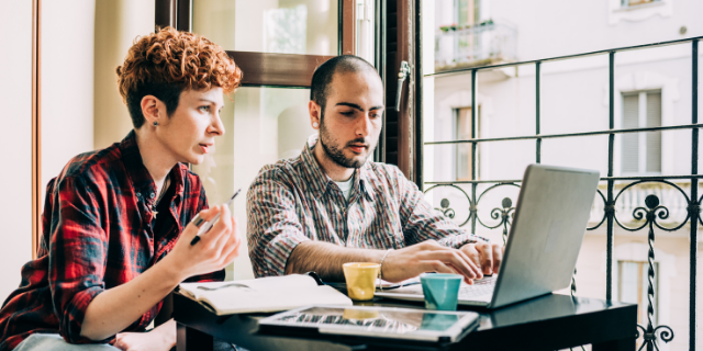 Homem e mulher trabalham em conjunto à frente do computador.