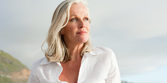 Mulher em cenário externo encara ponto aleatório ao horizonte.