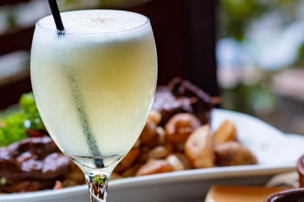 Taça com líquido branco e espuma na borda.