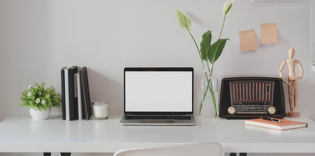 Mesa de trabalho com notebook, documentos e vaso de flores organizada
