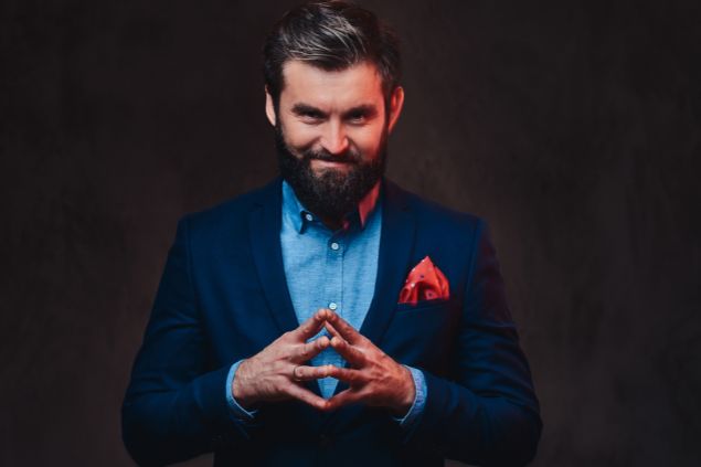 Imagem de um homem de terno em um fundo preto com semblante de manipulação