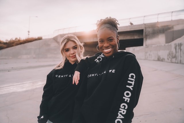 Mulher branca e mulher negra abraçadas.