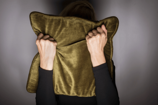 pessoa se escondendo atrás de uma almofada. 