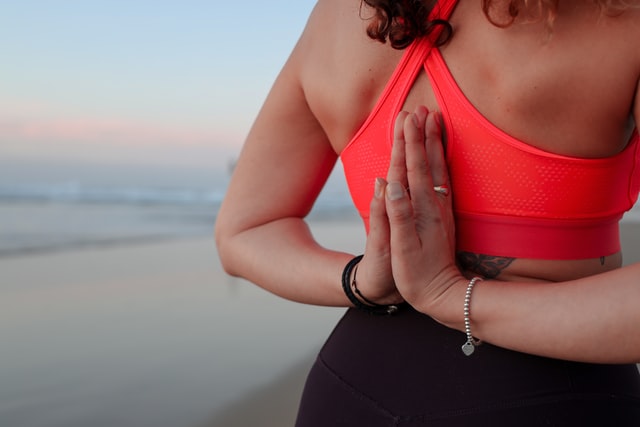 Mulher branca meditando na praia.