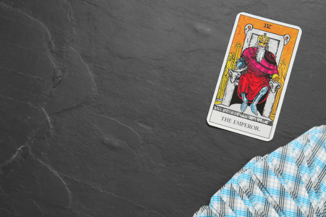 A carta O Imperador do Tarot está em destaque sobre uma superfície de pedra. Embaixo, há outras cartas de Tarot viradas para baixo.