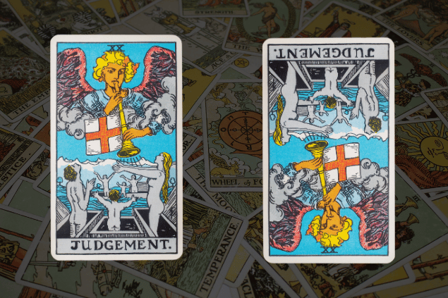 Montagem com a carta O Julgamento do Tarot na posição normal e outra carta O Julgamento na posição invertida. Ao fundo, há várias cartas de Tarot.