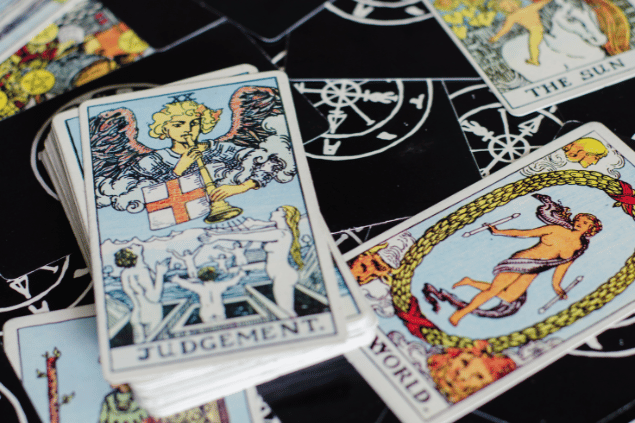 A carta O Julgamento do Tarot está sobre uma mesa em destaque e em cima de um baralho. Ao lado dela, há outras cartas espalhadas.