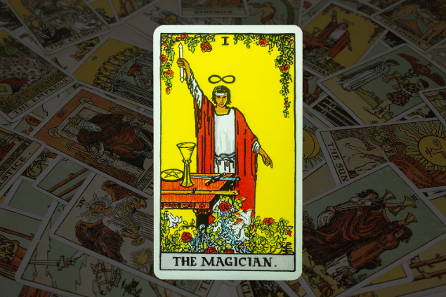 Montagem com a carta O Mago do Tarot na posição normal. Ao fundo, há várias cartas de Tarot.