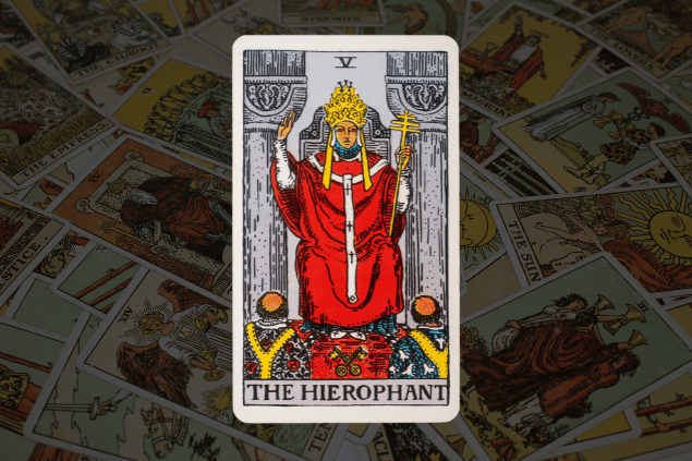Montagem com a carta O Papa do Tarot na posição normal. Ao fundo, há várias cartas de Tarot.