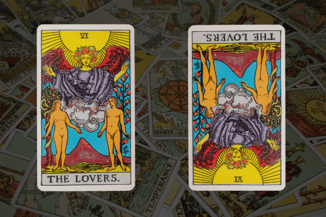 Montagem com a carta Os Enamorados do Tarot na posição normal e outra carta Os Enamorados na posição invertida. Ao fundo, há várias cartas de Tarot.