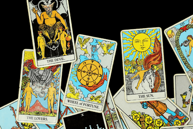 Várias cartas de Tarot estão espalhadas sobre uma superfície dar cor preta.