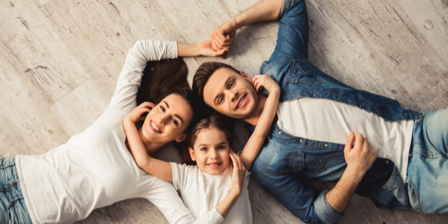 Menina entre um homem e uma mulher. Os três estão deitados sobre o chão.