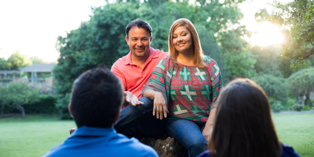 Homem e mulher sentados em frente de dois jovens. 